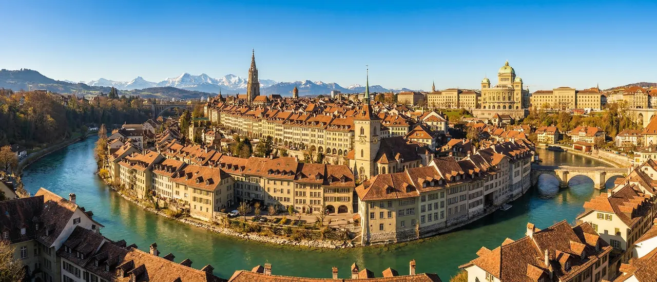 Luftaufnahme der Berner Altstadt, umflossen von der Aare, mit den Alpen im Hintergrund