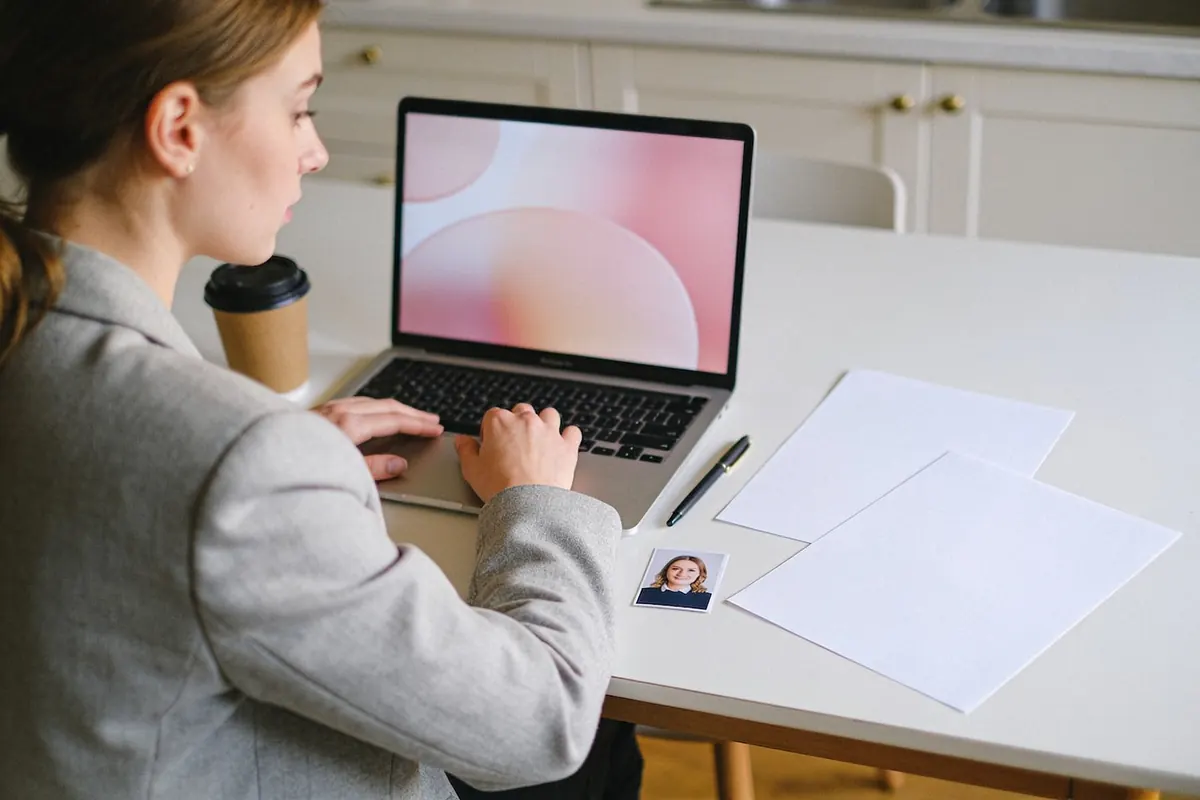 Eine junge Frau bereitet ihre Bewerbung mit Laptop und ausgedrucktem Lebenslauf vor