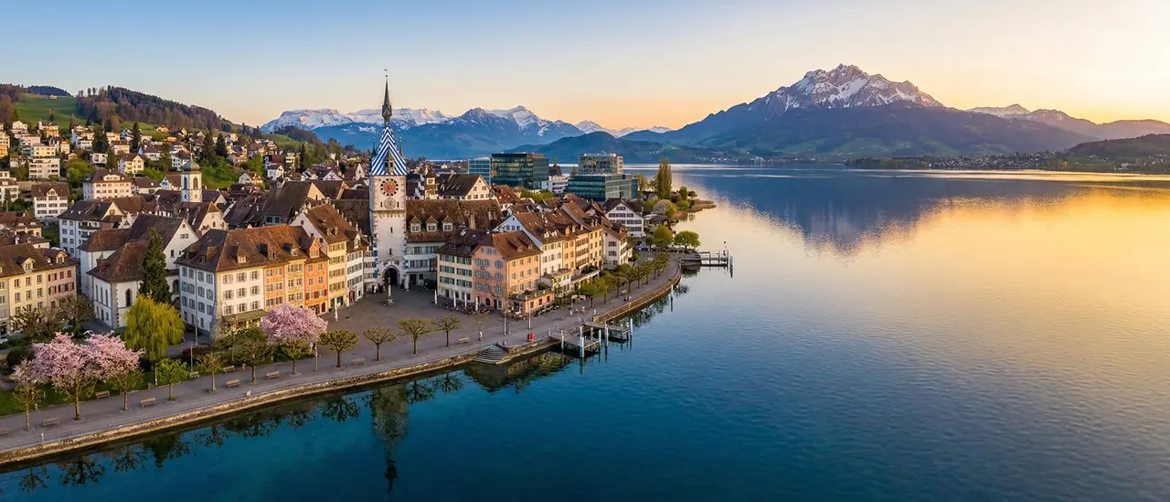Blick auf die Stadt Zug am See bei Sonnenuntergang mit den Alpen im Hintergrund